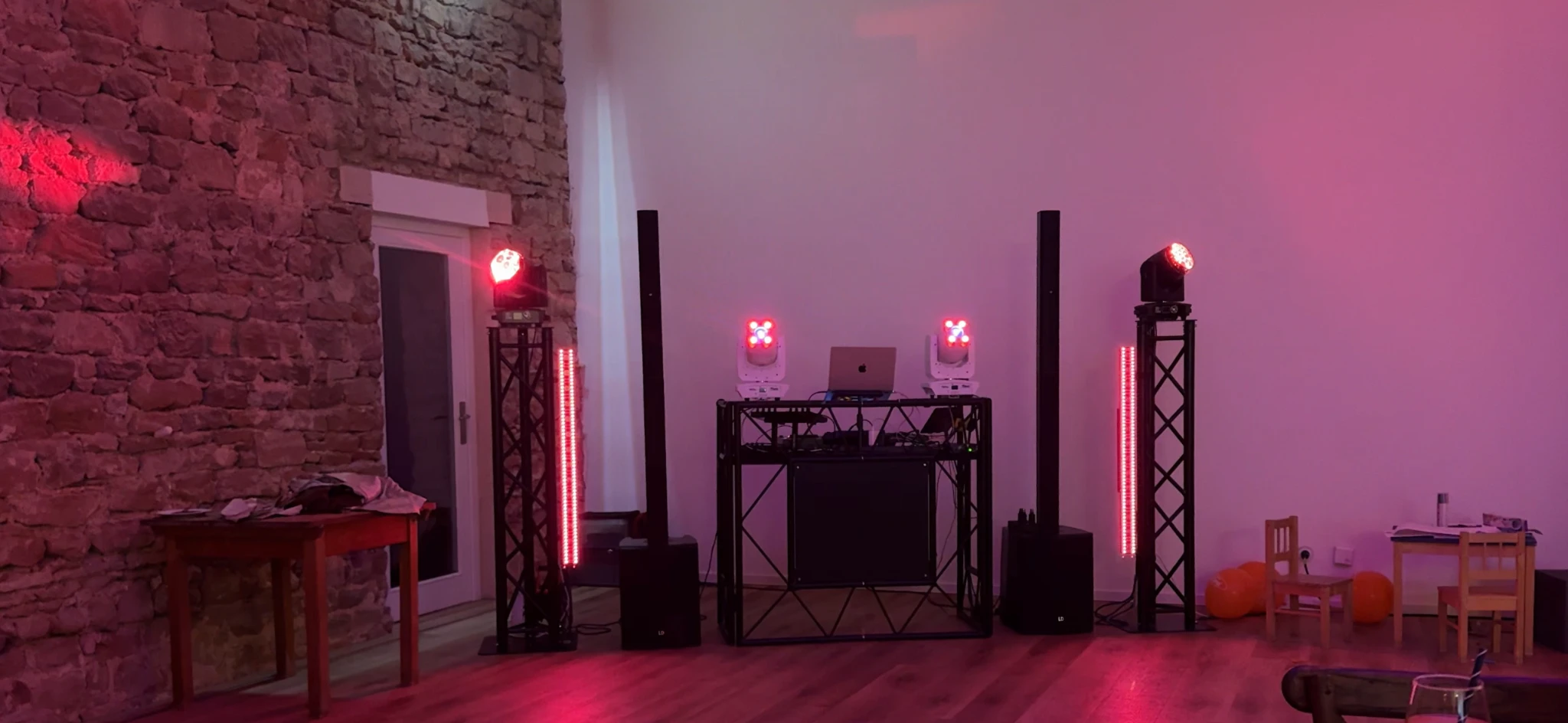 Aktuelles DJ-Setup mit rotem Licht vor einer Steinwand